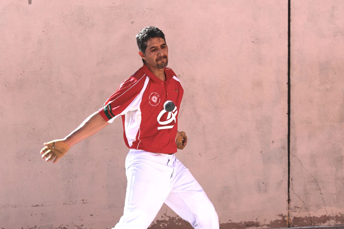 A Basque pilota player swings his hand at the ball.