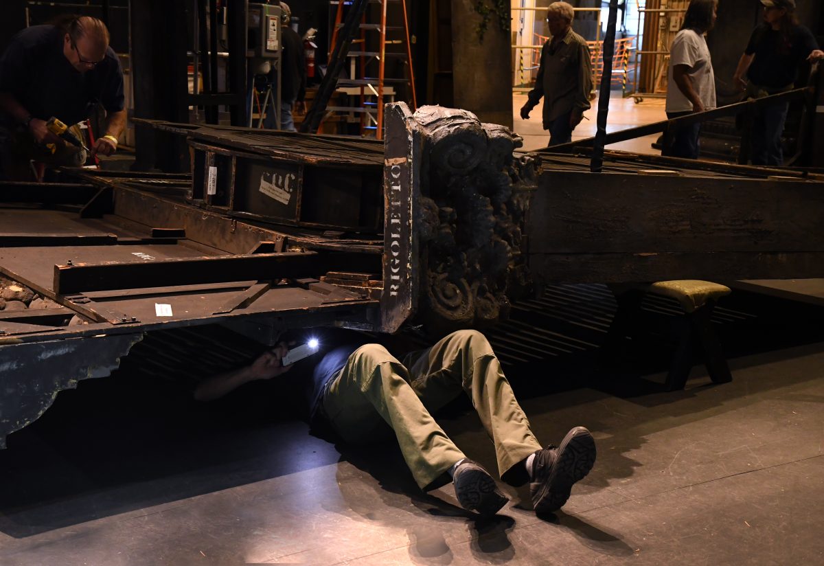 A man's legs stick out from under a set.