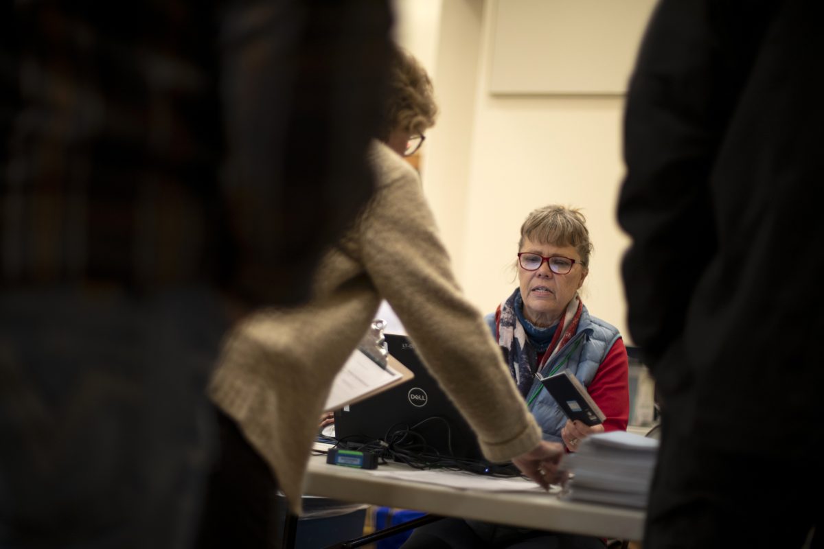 A poll worker holds onto at a woman's passport.