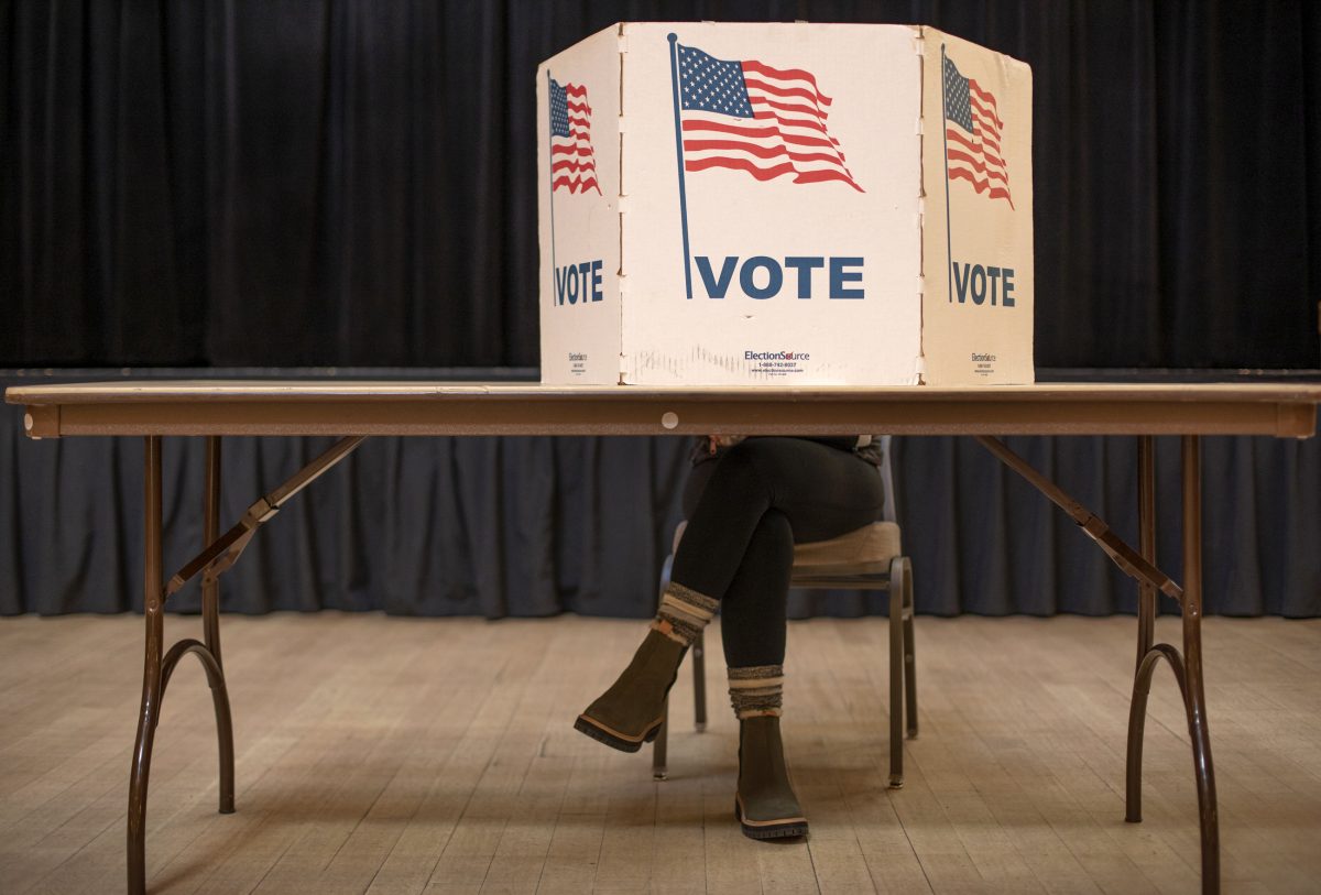 A woman crossers her feet as she fills out her ballot.