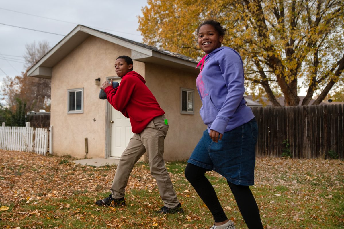 A boy goes to throw a football while his his walks near him.